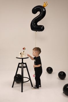 a little boy standing in front of a table with a cake on top of it