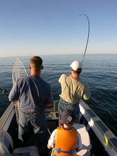 two men and a boy fishing on the back of a boat