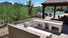 an outdoor kitchen is built into the side of a house with a pool in the background