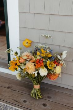 a bouquet of flowers sitting on top of a wooden table next to a door way