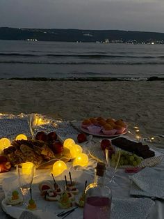 a table set up on the beach with food and drinks for two people to enjoy