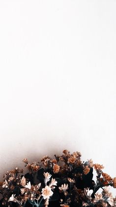 a vase filled with lots of flowers on top of a wooden table next to a white wall