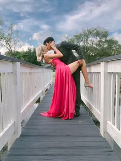 a man and woman kissing on a bridge