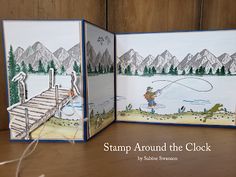 two handmade cards with fishing scene and mountains in the background, on a table