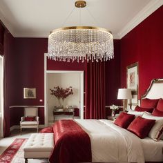 a bedroom decorated in red and white with a chandelier hanging from the ceiling