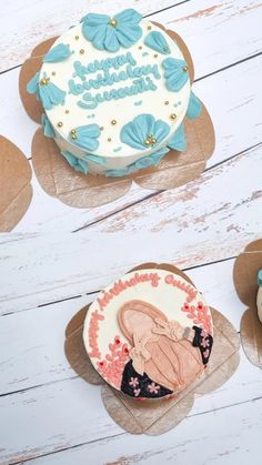 three decorated birthday cakes sitting on top of brown paper doily with blue and white frosting