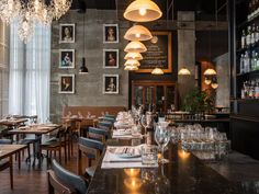 an empty restaurant with many tables and chairs, chandeliers hanging from the ceiling