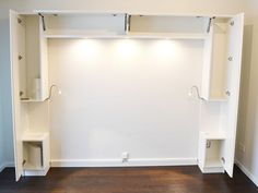 an empty room with white walls and open shelves on the wall, along with wood flooring