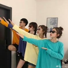 four people standing in front of a black door with their arms stretched out to the side