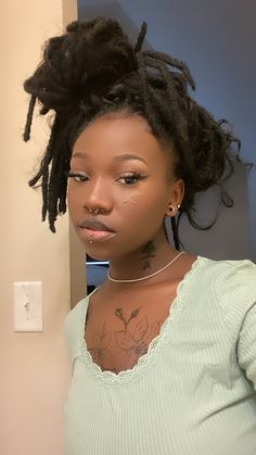 a woman with dreadlocks standing in front of a wall and looking at the camera