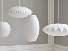 three white paper lanterns hanging from strings in a room with gray walls and flooring