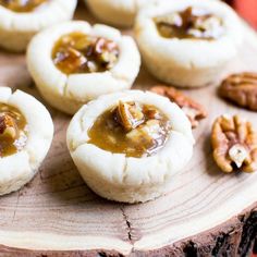 small cookies with pecans and caramel are on a wooden board, ready to be eaten