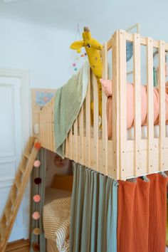 a child's bed with a giraffe hanging from the top