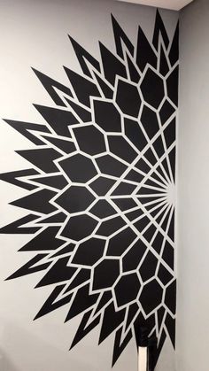 a black and white wall with an artistic design on it's side, in the corner of a room