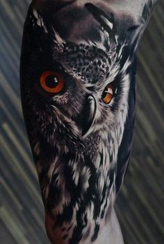 an owl with orange eyes is shown on the leg and it's tattoo design