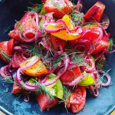 a blue bowl filled with red onions and sliced up tomatoes on top of a wooden table