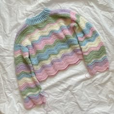 a colorful sweater laying on top of a white sheet