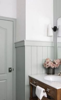 a bathroom with a sink, mirror and flowers on the counter in front of it