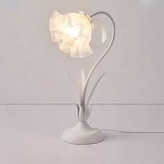 a white table lamp with a flower shaped light bulb on it's end and a cord attached to the base