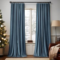 a living room with a christmas tree in the corner and blue curtains hanging on the windowsill