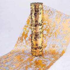 a tall gold vase sitting on top of a white table covered in yellow and silver paint