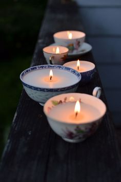 three tea lights are sitting on a table with bowls full of water and candles in them