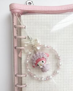 a pink binder with a keychain and an animal charm hanging from it's side