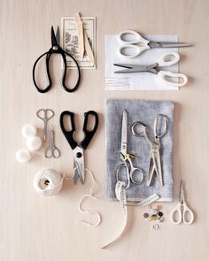 several pairs of scissors are sitting on a table next to some thread and other crafting supplies