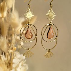 Bring out your inner sun goddess with these geometric statement earrings. This design features brushed brass sun ray motifs paired with coral blush glass teardrops for an elegant sparkle. Product Details: *gold surgical stainless steel earring hooks *hypoallergenic and nickel-free *raw brass components *glass teardrop beads *drop length: 7.5 cm Jewelry Care: To keep brass jewelry looking its best, remove jewelry before bathing, exercising or swimming to prevent premature tarnishing. Apply cosmet Geometric Statement Earrings, Sun Goddess, Brass Components, Celestial Sun, Coral Blush, Asymmetrical Earrings, Witchy Jewelry, Teardrop Beads, Sun Rays