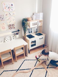 a young boy plays with toys in his playroom at the same time as he sits on the floor