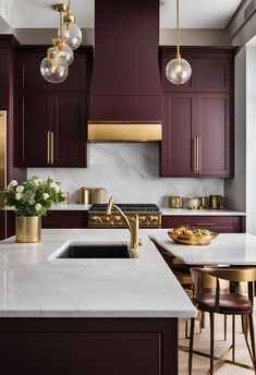 a kitchen with marble counter tops and dark purple cabinetry, gold accents on the cabinets