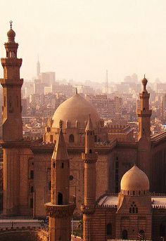 an old building with two towers in front of a large cityscape that has tall buildings on both sides