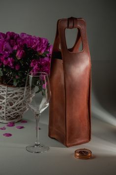 a wine glass and bottle in front of a basket with purple flowers