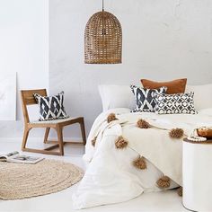 a bed with white sheets and pillows on top of it next to a wooden chair