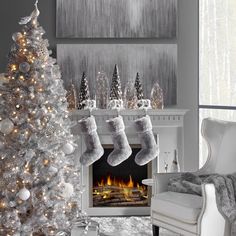 a white christmas tree with stockings hanging from it's sides in front of a fireplace