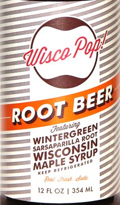 a bottle of root beer sitting on top of a white and orange striped table cloth