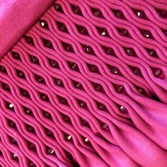 closeup of pink fabric with metal rivets on the back and side of it