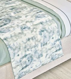 a bed with a white and blue comforter on top of it