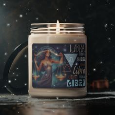 a lit candle with the zodiac sign libra in front of it on a table