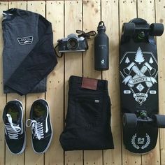 a skateboard, camera, and other items are laid out on a wooden floor