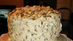 a close up of a cake on a plate with frosting and nuts all over it