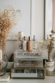 various beauty products are displayed in glass containers on a table with flowers and other items