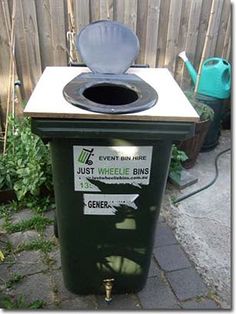 a green trash can sitting in the middle of a yard