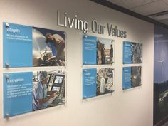 a group of people standing next to a wall with posters on it that say living our values