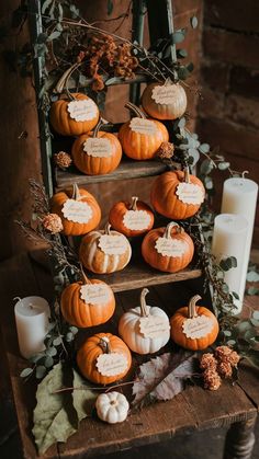 pumpkins are arranged on three tiered shelves in front of candles