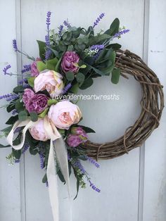 a wreath with pink and purple flowers hanging on a door