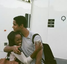 two people hugging each other in front of a white truck with their arms around one another