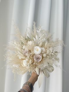 a person holding a bouquet of flowers in their hand with white curtains behind them and the curtain is closed