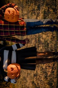 three people wearing pumpkin heads standing in the grass