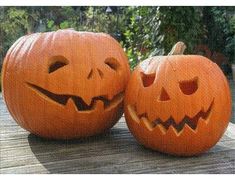 two carved pumpkins sitting on top of a wooden table